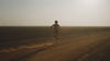 A lone runner on a dusty dirt road at golden hour
