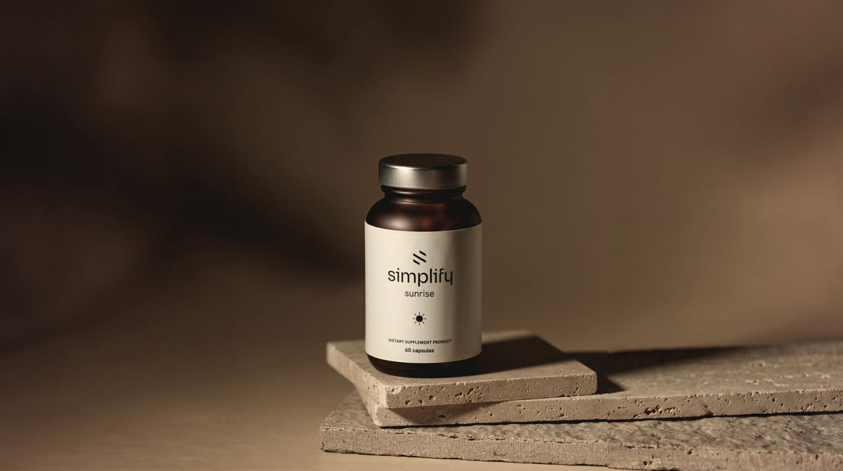 Simplify Sunrise vitamin bottle on stacked travertine slabs, warm morning light