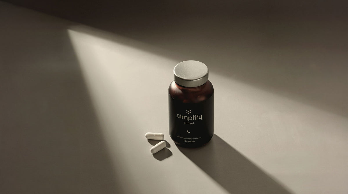 Simplify Sunset vitamin bottle with two capsules in a shaft of evening light